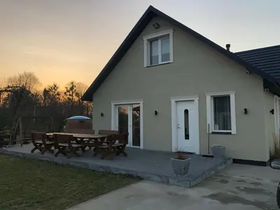 a white house with a picnic table in front of it at Wind Mood in Klebiškis