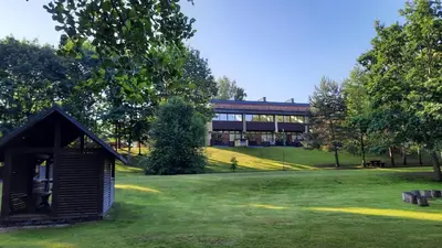 a building in the middle of a field with trees at Kambarys Šiaurėje in Kaltanėnai