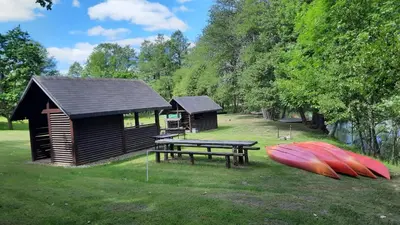 a cabin with a picnic table and a bench and a canoe at Kambarys Šiaurėje in Kaltanėnai