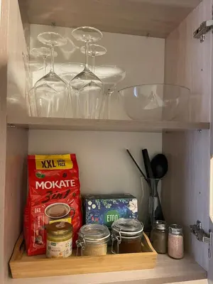 a cabinet with bowls and wine glasses and food at MM Apartments in Kaunas