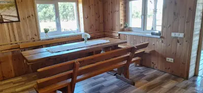 a dining room with a wooden table and two benches at Gėlūnų sodyba in Gelunai