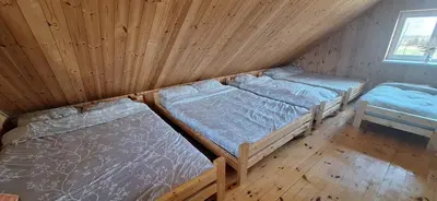 a room with two beds in a wooden cabin at Gėlūnų sodyba in Gelunai
