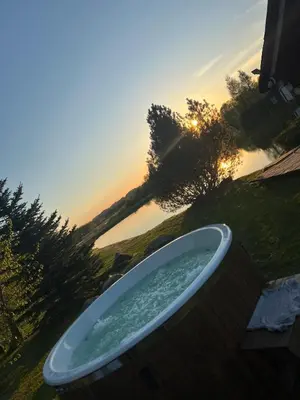 a bath tub with the sunset in the background at Sekioniu Ranch - Cosy Wooden Cabins in Lithuania in Sekionys