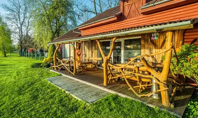 a wooden deck with chairs on a house at Sekioniu Ranch - Cosy Wooden Cabins in Lithuania in Sekionys