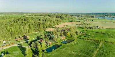 an aerial view of a farm with a river and trees at Sekioniu Ranch - Cosy Wooden Cabins in Lithuania in Sekionys