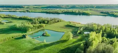 an aerial view of a large lake in a field at Sekioniu Ranch - Cosy Wooden Cabins in Lithuania in Sekionys