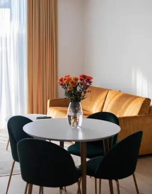 a table and chairs with a vase of flowers on it at Parko Aveniu Apartamentai B2 in Birštonas