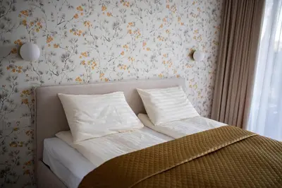 a bed with white sheets and pillows in a bedroom at Parko Aveniu Apartamentai B2 in Birštonas