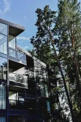 a glass building with trees in the background at Parko Aveniu Apartamentai B2 in Birštonas
