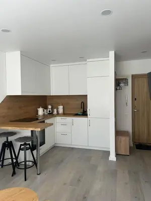a kitchen with white cabinets and a wooden table at AB Apartment in Marijampolė