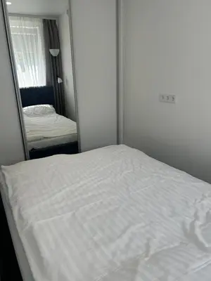 a white bed in a room with a mirror at AB Apartment in Marijampolė