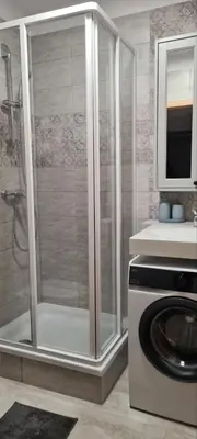 a shower in a bathroom with a washing machine at Vita apartment in Vilnius