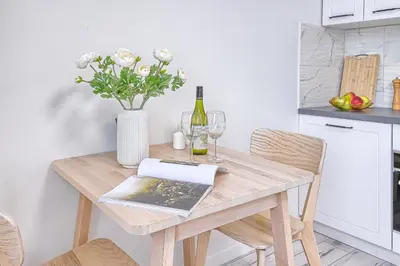 a wooden table with a vase of flowers and wine glasses at Old Town Edvin Apartments in Vilnius
