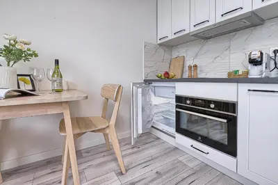 a kitchen with white cabinets and a wooden table and chair at Old Town Edvin Apartments in Vilnius