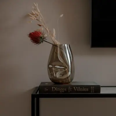a vase with a flower sitting on top of a book at Spacious luxury apartment with parking in Vilnius