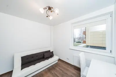 a white living room with a window and a couch at Erdvus triju kambariu butas, naujos statybos name in Kaunas