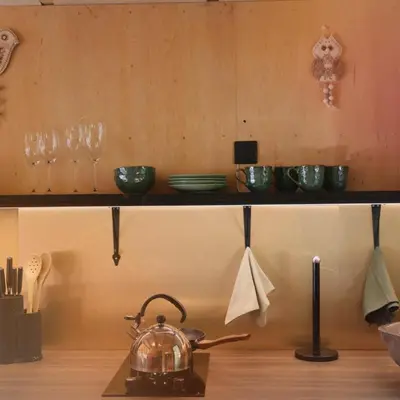 a kitchen with a tea kettle and glasses on a shelf at Here & Now Tiny House in Sudvariškės