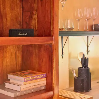 a book shelf with a stack of books and wine glasses at Here & Now Tiny House in Sudvariškės
