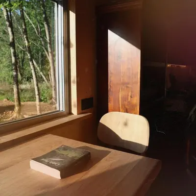 a book sitting on a table next to a window at Here & Now Tiny House in Sudvariškės