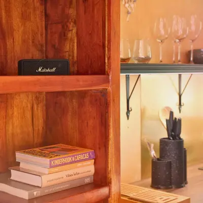 a book shelf with books and wine glasses on it at Here & Now Tiny House in Sudvariškės
