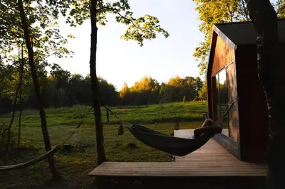 a person laying in a hammock in a tiny house at Here & Now Tiny House in Sudvariškės