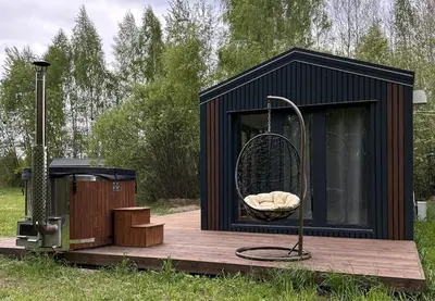 a black tiny house on a wooden deck at Spalvotas Beržas in Lyduokiai