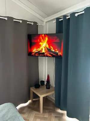 a room with a tv with a fire on the wall at Spalvotas Beržas in Lyduokiai