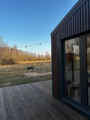 a black house with a deck and a bench at Spalvotas Beržas in Lyduokiai