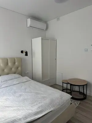 a white bedroom with a bed and a table at Užupio apartamentai Nemokamas parkingas in Vilnius