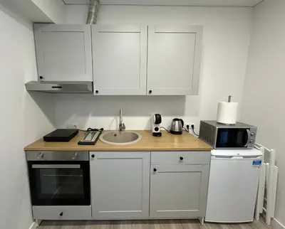 a kitchen with white cabinets and a sink and a microwave at Užupio apartamentai Nemokamas parkingas in Vilnius