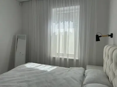 a white bedroom with a bed and a window at Užupio apartamentai Nemokamas parkingas in Vilnius