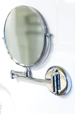 a round mirror hanging on a bathroom wall at HOF Apartments in Kaunas