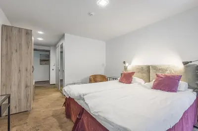 a bedroom with a large bed with white sheets and pink pillows at HOF Apartments in Kaunas