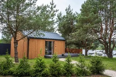 a wooden house with a black roof at Nemunas Glamping in Kriemala