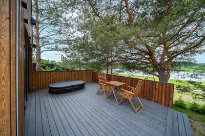 a wooden deck with a table and chairs and a bench at Nemunas Glamping in Kriemala