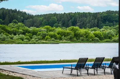 a group of chairs sitting next to a body of water at Nemunas Glamping in Kriemala