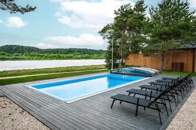 a swimming pool with chairs on a wooden deck at Nemunas Glamping in Kriemala