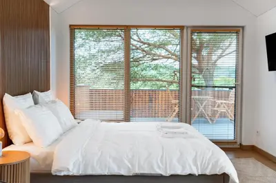 a bedroom with a white bed and a large window at Nemunas Glamping in Kriemala