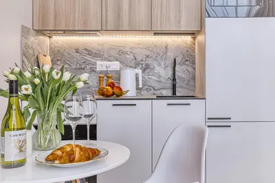 a white kitchen with a table with a plate of food at Sunny loft 2 x 24x7 x Free parking x Close to old town in Vilnius