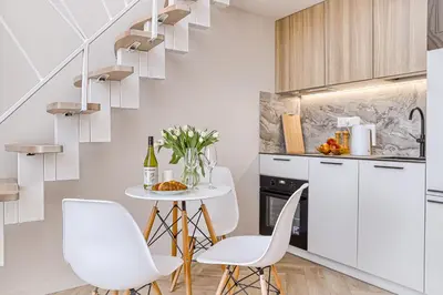 a white kitchen with white chairs and a table at Sunny loft 2 x 24x7 x Free parking x Close to old town in Vilnius