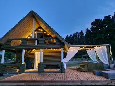 a house with a deck with a string of lights at Atostogų namelis SAMANOTA PAMIŠKĖ, pirtis ir kubilas papildomai in Romaškiai