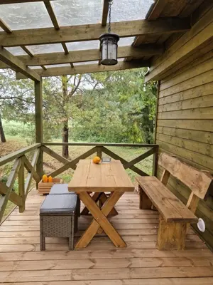 a picnic table and benches on a wooden deck at Atostogų namelis SAMANOTA PAMIŠKĖ, pirtis ir kubilas papildomai in Romaškiai
