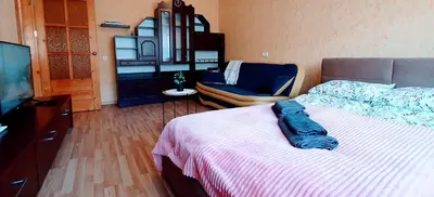 a bedroom with a bed and a chair and a television at SUN CITY Varpo Apartment in Šiauliai