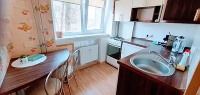 a kitchen with a sink and a counter with chairs at SUN CITY Varpo Apartment in Šiauliai