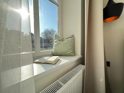 a window seat with a book and a pillow at City central apartment in Vilnius
