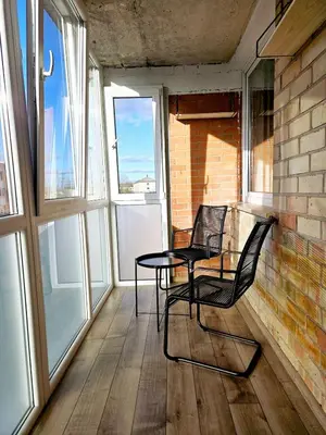 a room with two chairs and a table in front of windows at Cozy Corner in Šiauliai