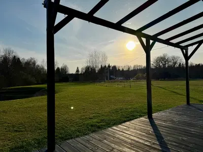 a gazebo with the sun setting over a field at MOSS lodge in Naujasėdžiai