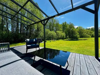 a patio with a chair and a pond at MOSS lodge in Naujasėdžiai