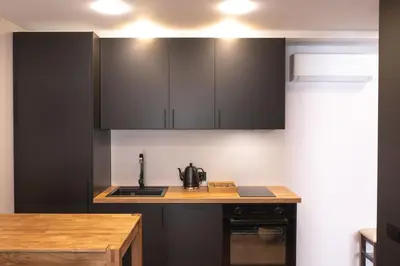 a kitchen with black cabinets and a wooden counter top at Euforia - Jacuzzi apartment Ukmergė in Ukmergė