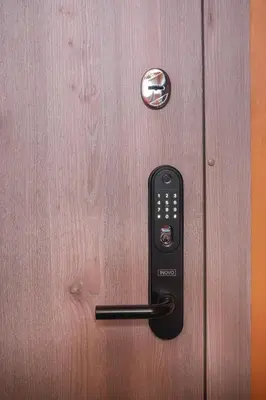 a black remote control on a wooden door at Euforia - Jacuzzi apartment Ukmergė in Ukmergė